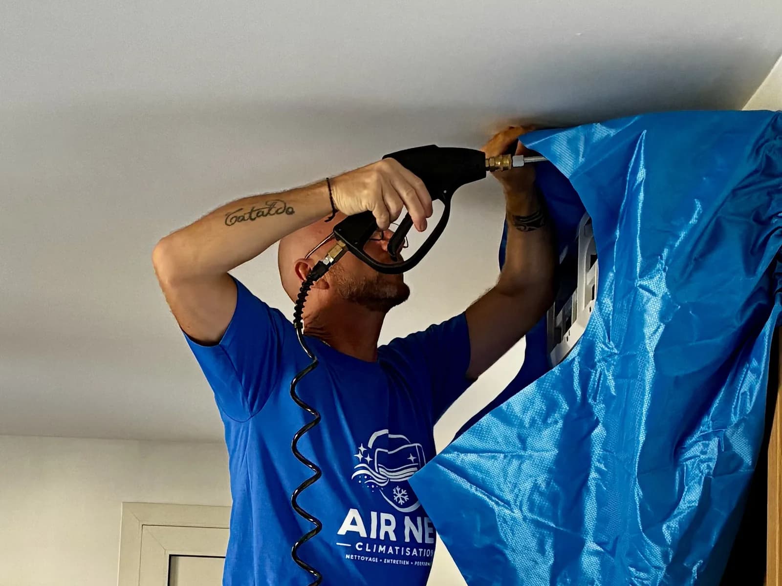 Technicien Air Net Climatisation nettoyant une unité intérieure avec une protection étanche