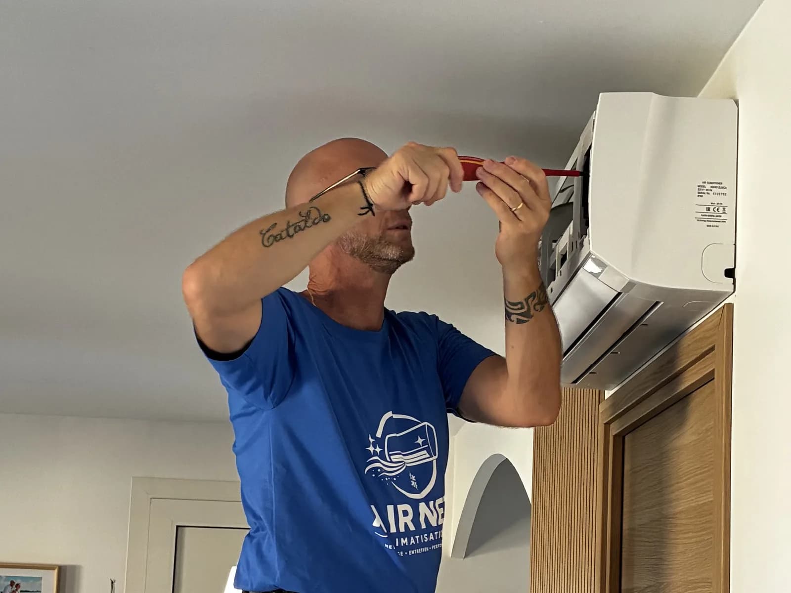Technicien Air Net Climatisation ouvrant une climatisation murale pour un nettoyage en profondeur